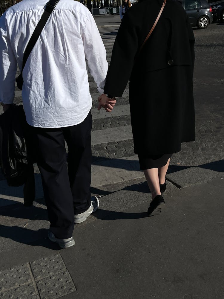 A Couple Holding Hands In A City 