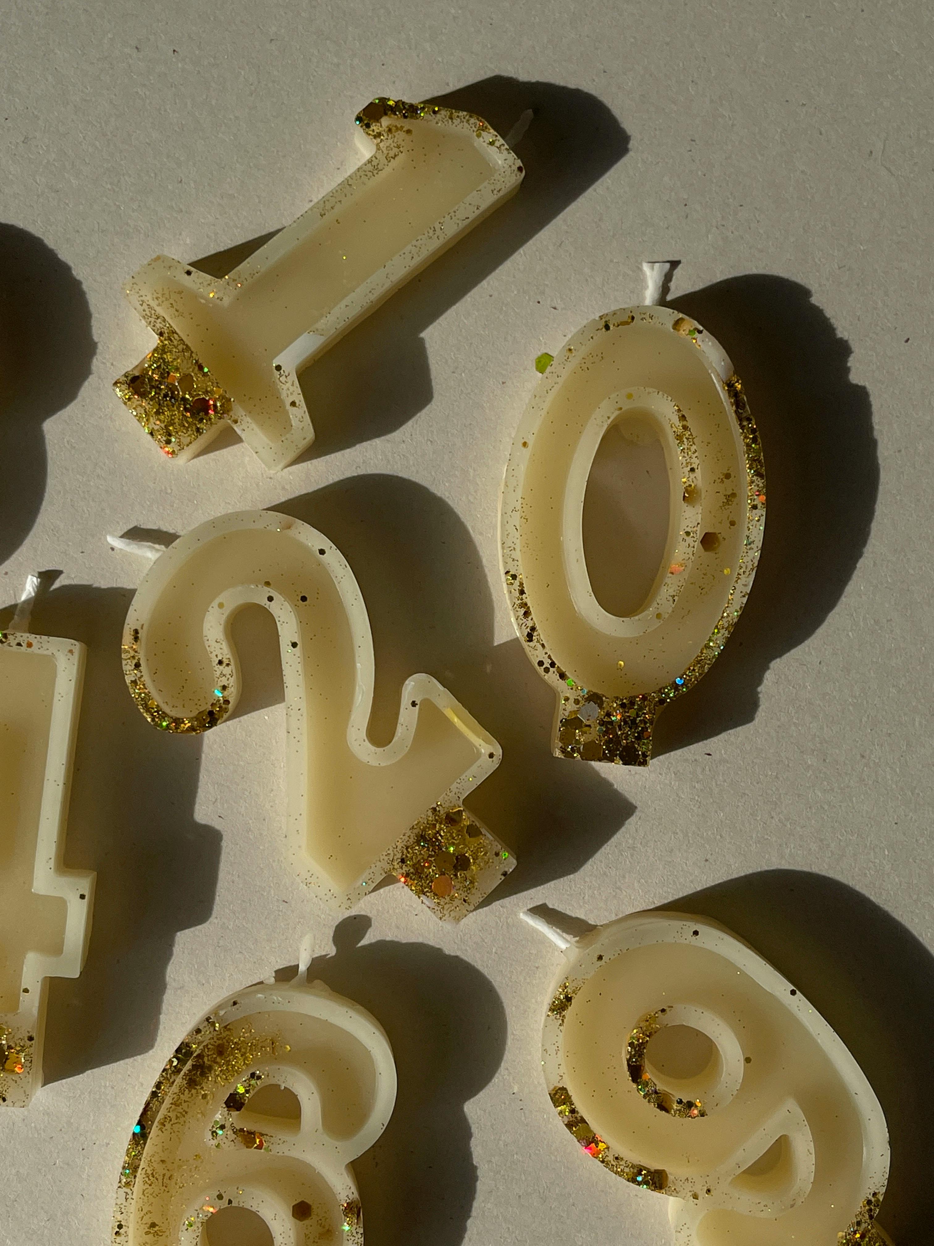 Close-up of glittery number-shaped candles in sunlight, ideal for festive occasions.