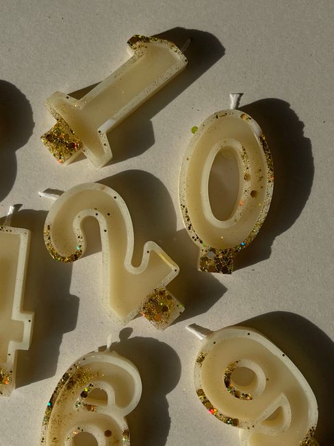 Close-up of glittery number-shaped candles in sunlight, ideal for festive occasions.