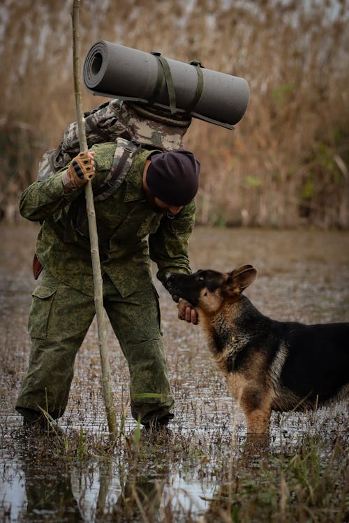 Man in Camouflage Clothing with a Dog 