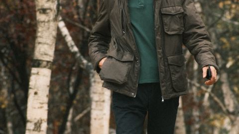 Senior man in casual attire walks along a scenic forest path in autumn.