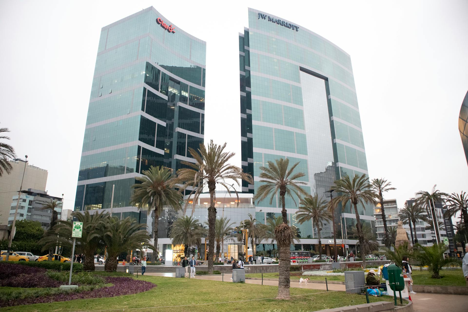 Modern architecture of JW Marriott Hotel in downtown Lima, Peru, surrounded by palm trees.