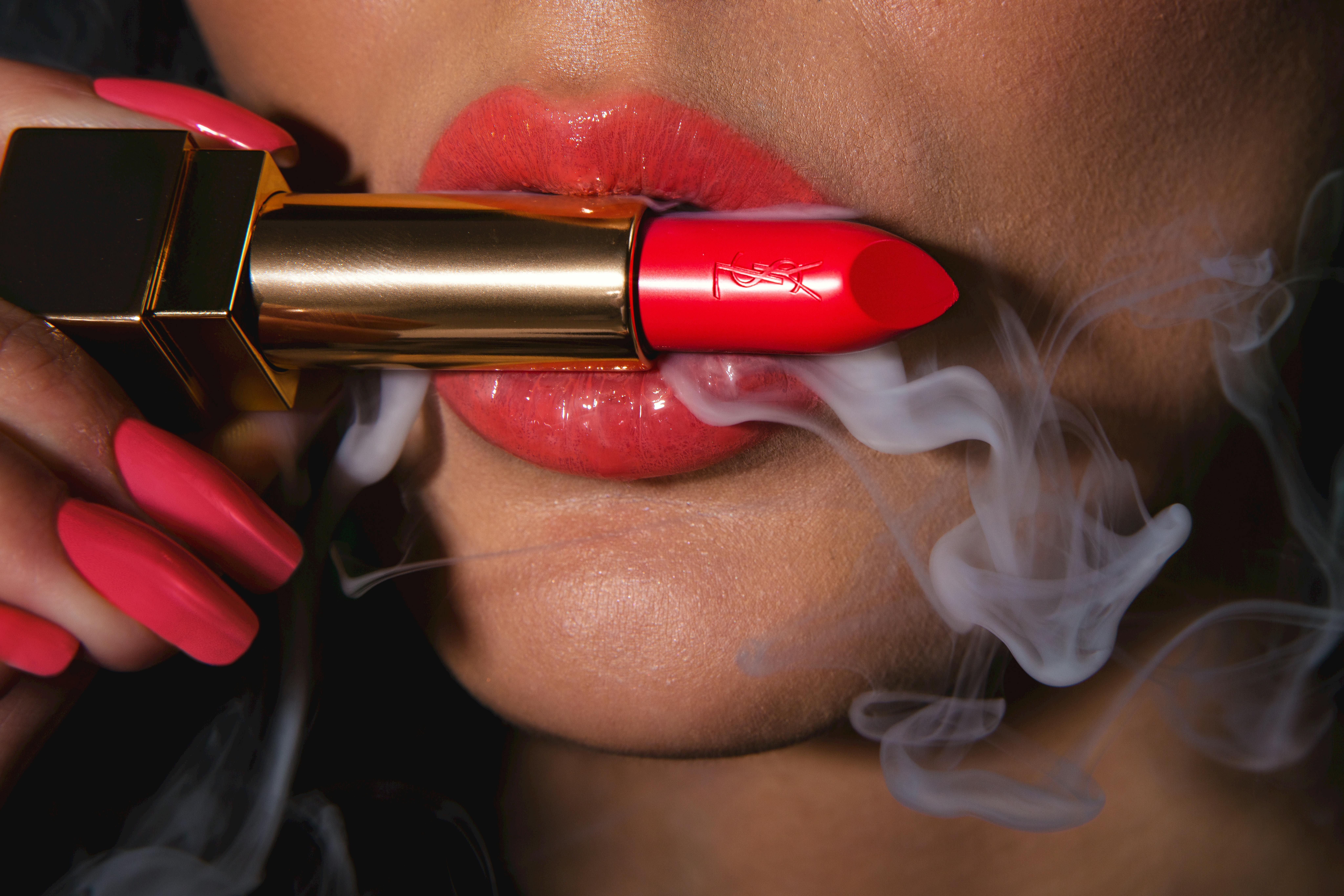 Vibrant red lipstick on lips with smoke effect, highlighting cosmetics and beauty.