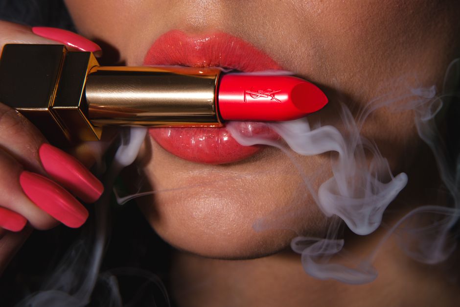 Vibrant red lipstick on lips with smoke effect, highlighting cosmetics and beauty.