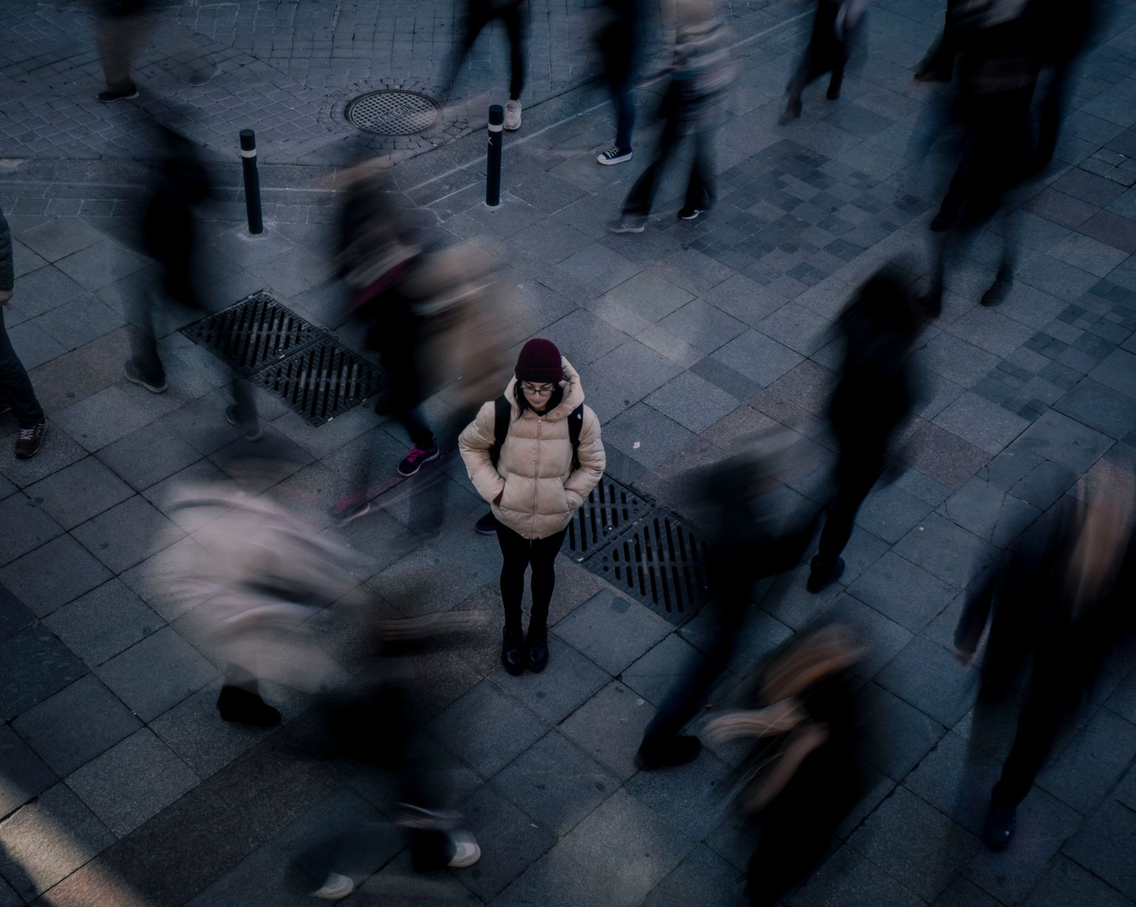 Woman standing still as a blurred crowd walks past — signal in noise.