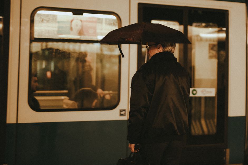 A commuter holding an umbrella while standing near a metro train