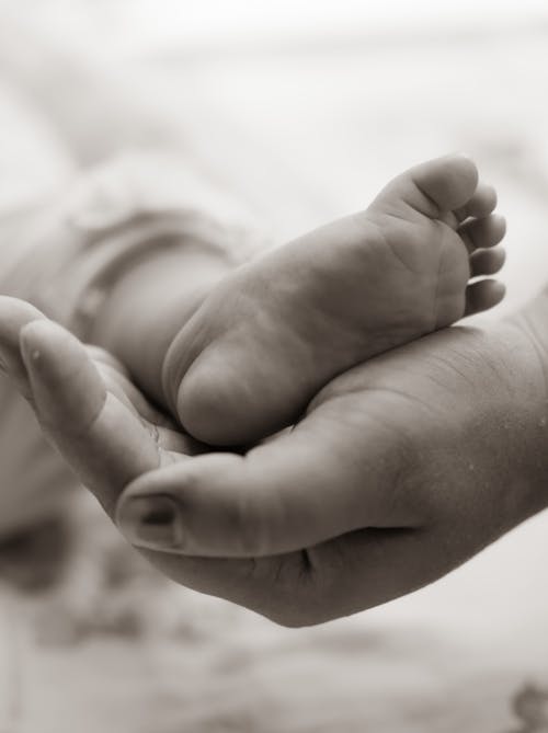 Close-Up Shot of a Person Holding Baby's Little Foot