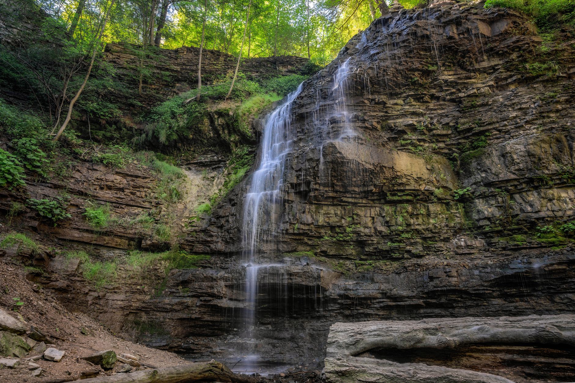 Scenic waterfall cascading over rocky cliffs in a lush forest in Hamilton, Ontario, Canada.