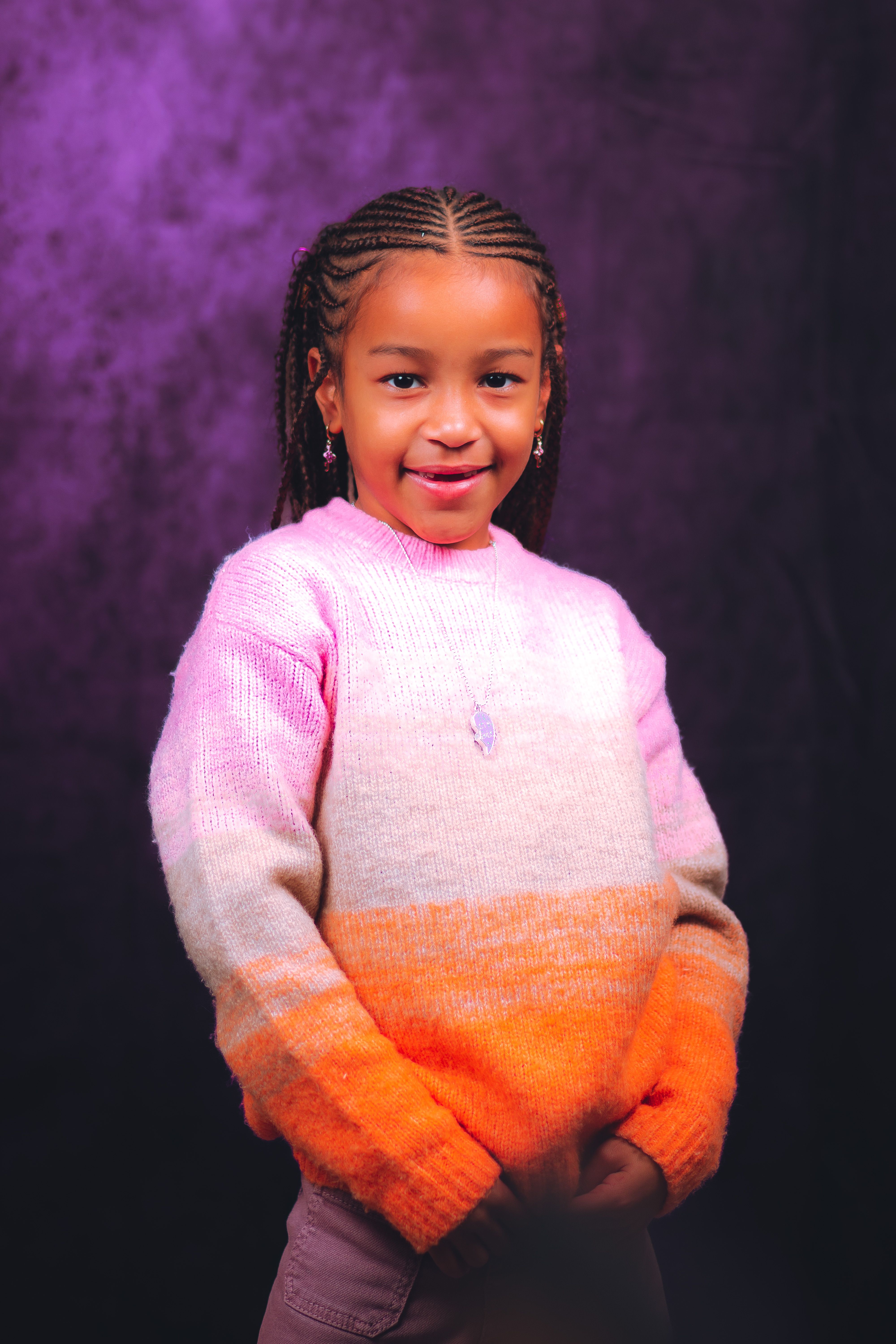 Beautiful portrait of a smiling girl wearing a pink and orange sweater with a vibrant background.
