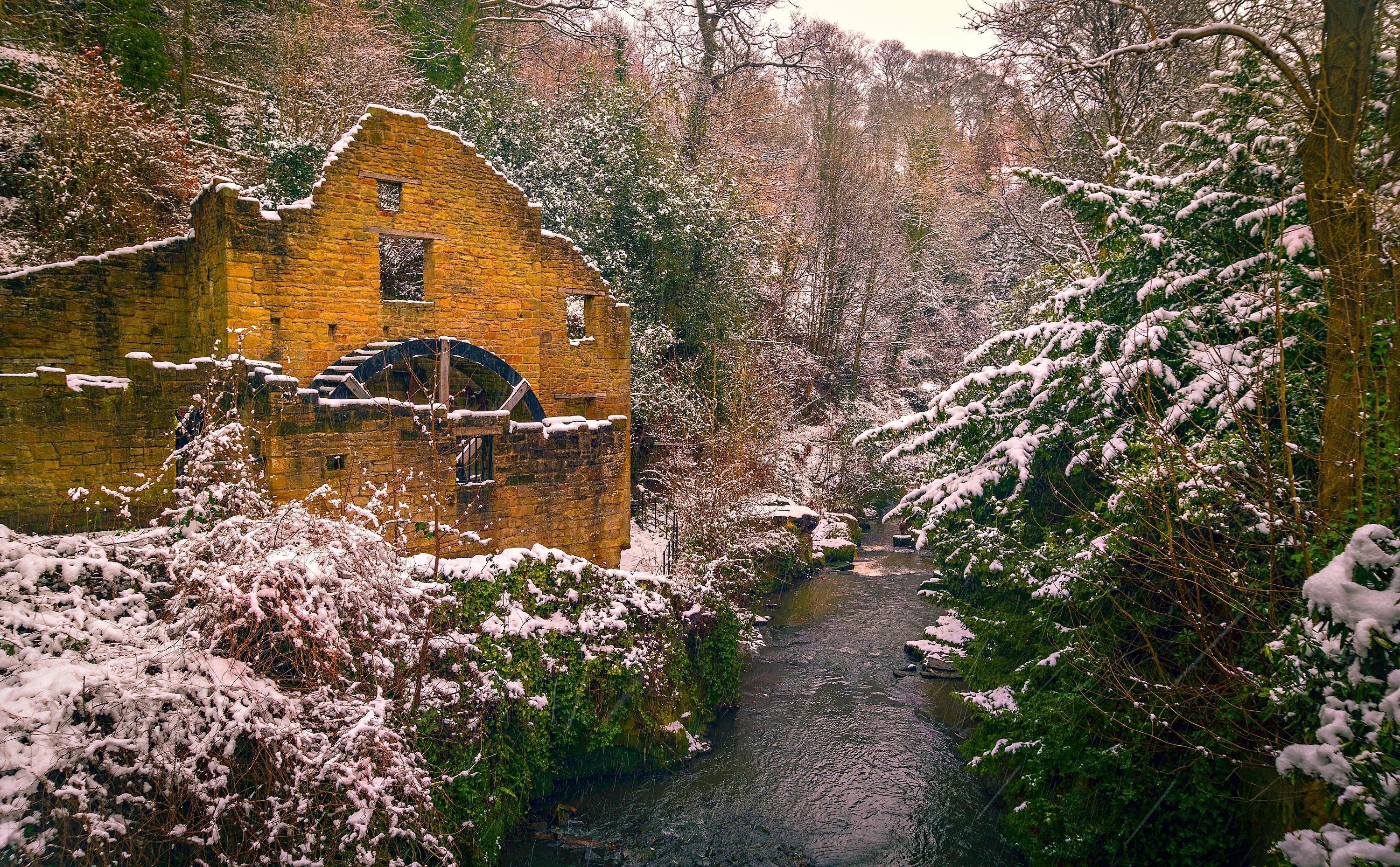 白雪皑皑的河流和郁郁葱葱的森林旁，废弃的石磨是在冬天捕获的