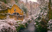 白雪皑皑的河流和郁郁葱葱的森林旁，废弃的石磨是在冬天捕获的