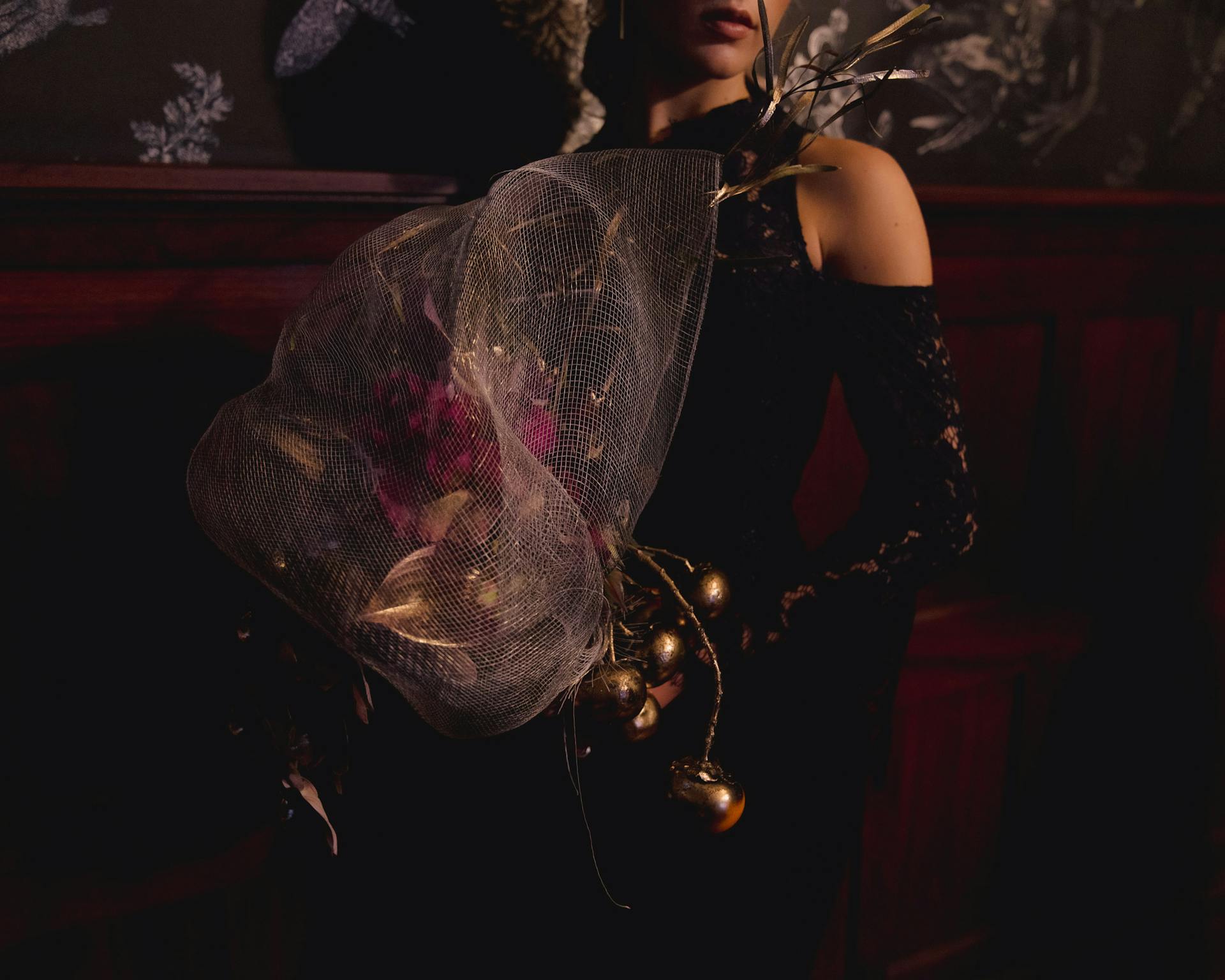 Dark and moody portrait of a woman in formal attire holding a unique floral bouquet.