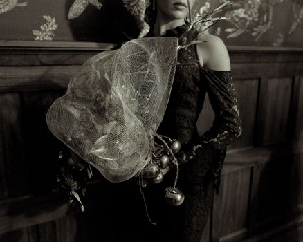 Stylized portrait of a woman in formal attire holding a creative bouquet.