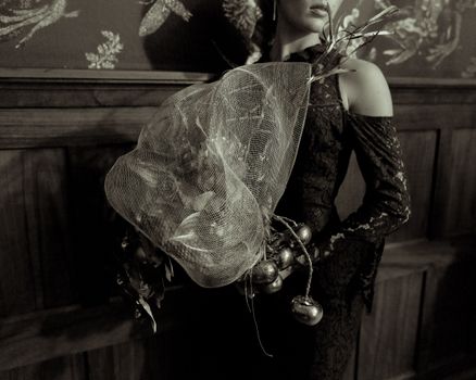 Sepia-toned portrait of a woman holding an ornate bouquet in a vintage elegant setting.