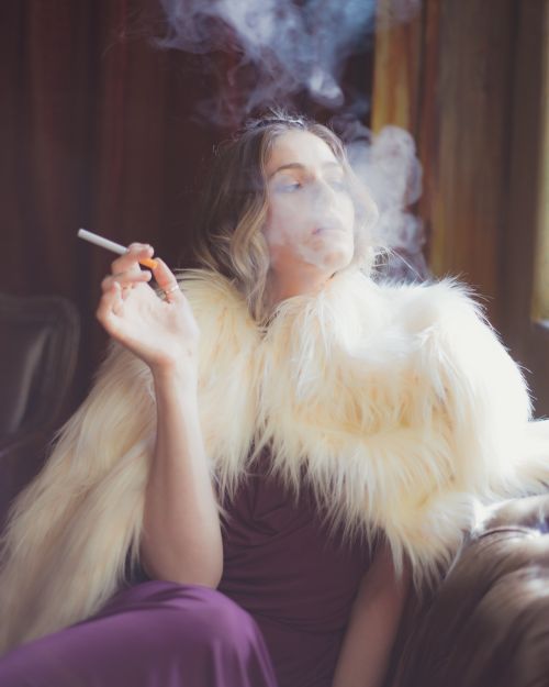 Free A woman in formal attire smokes elegantly indoors, exuding luxury and fashion. Stock Photo