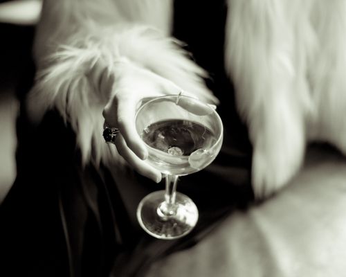 Free Close-up of a woman's hand holding a cocktail glass with a fur coat, exuding elegance and luxury. Stock Photo