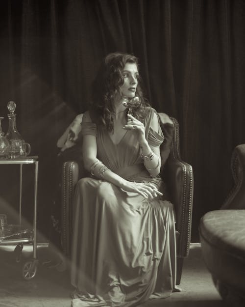 A Woman Holding a Drink while Sitting 