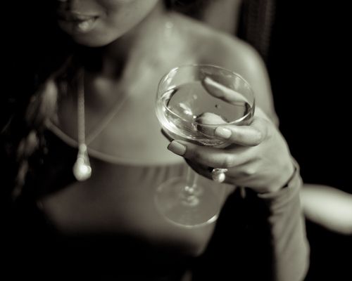 Free A stylish woman elegantly holding a cocktail glass in a dimly lit setting. Stock Photo