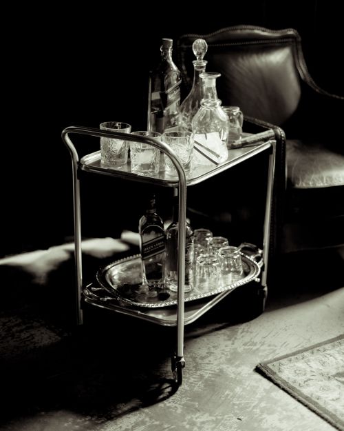 Free Vintage liquor trolley with whiskey decanters and glassware in grayscale lighting. Stock Photo