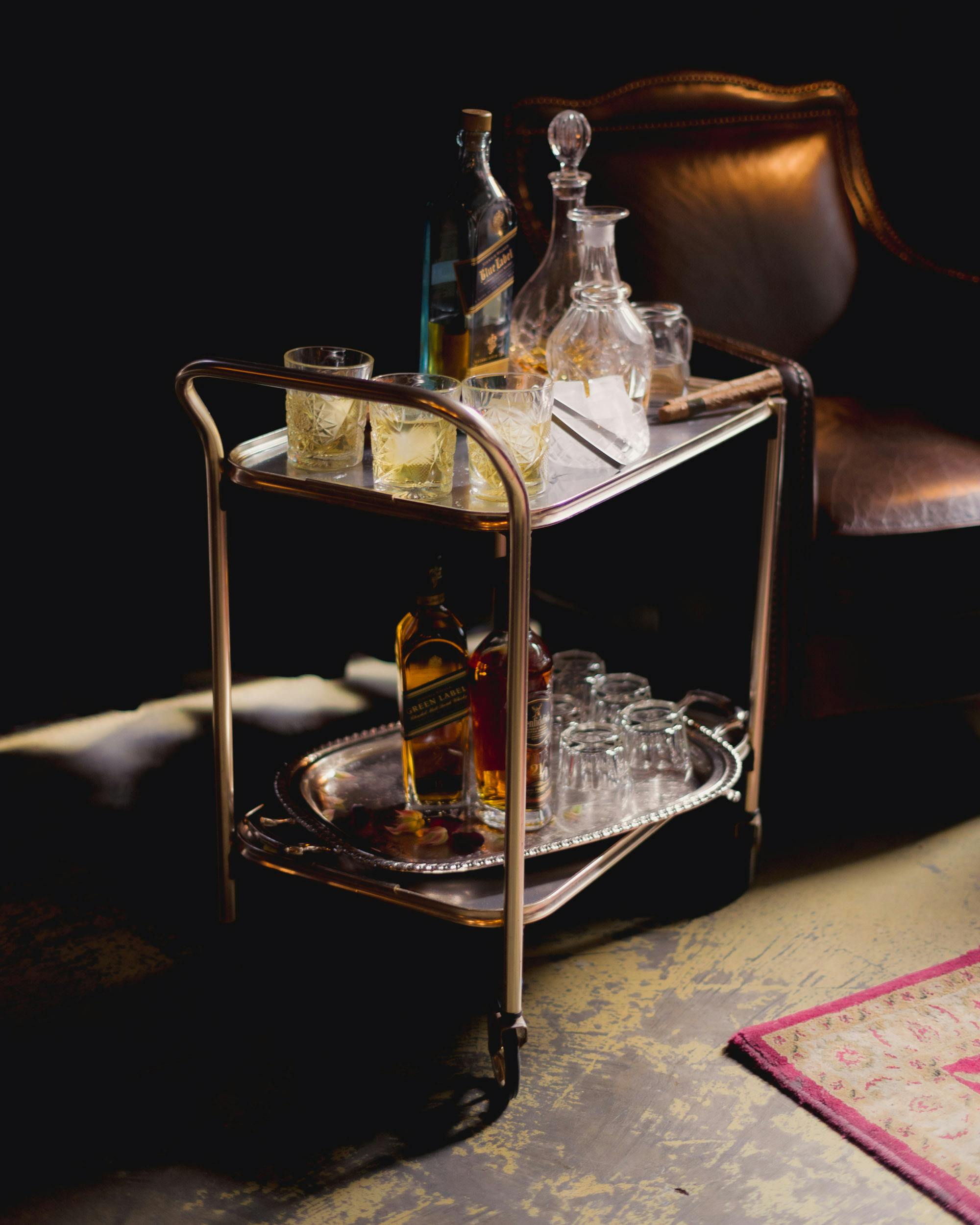 A classic trolley with bottles and glassware waiting in a low-lit room