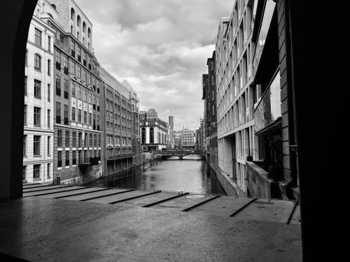 Free Black and white view of canal flanked by historical buildings under cloudy skies. Stock Photo