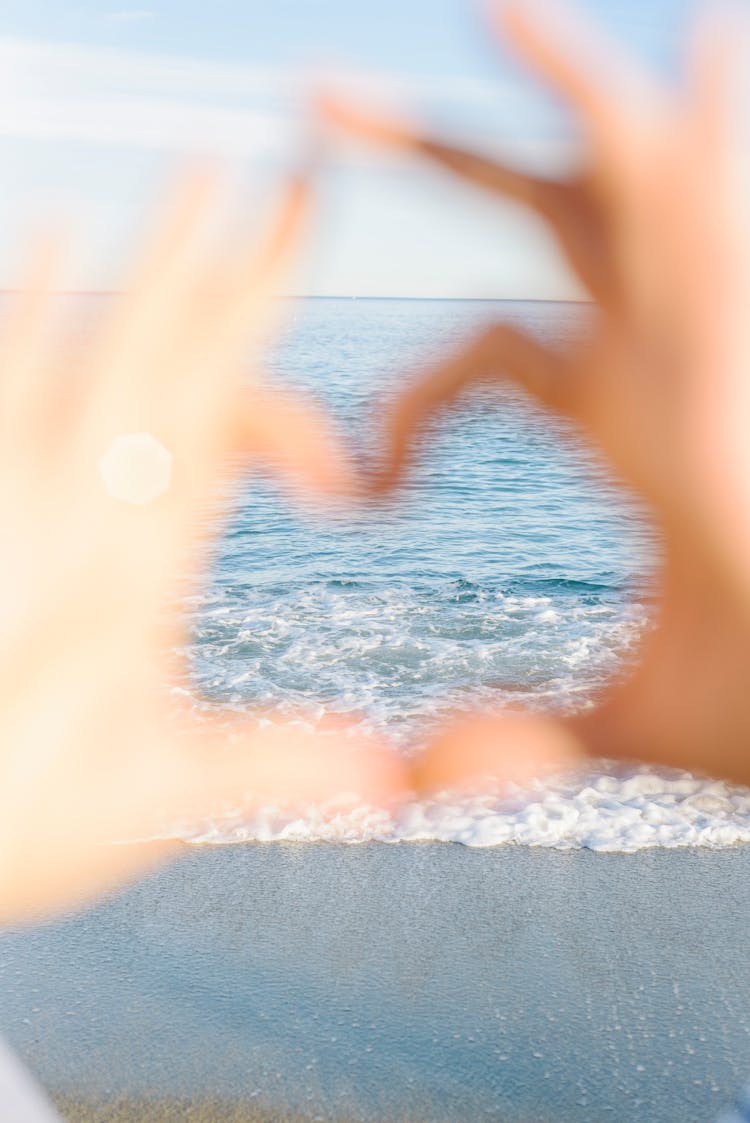 Hands Making Heart Shape On Sea Shore