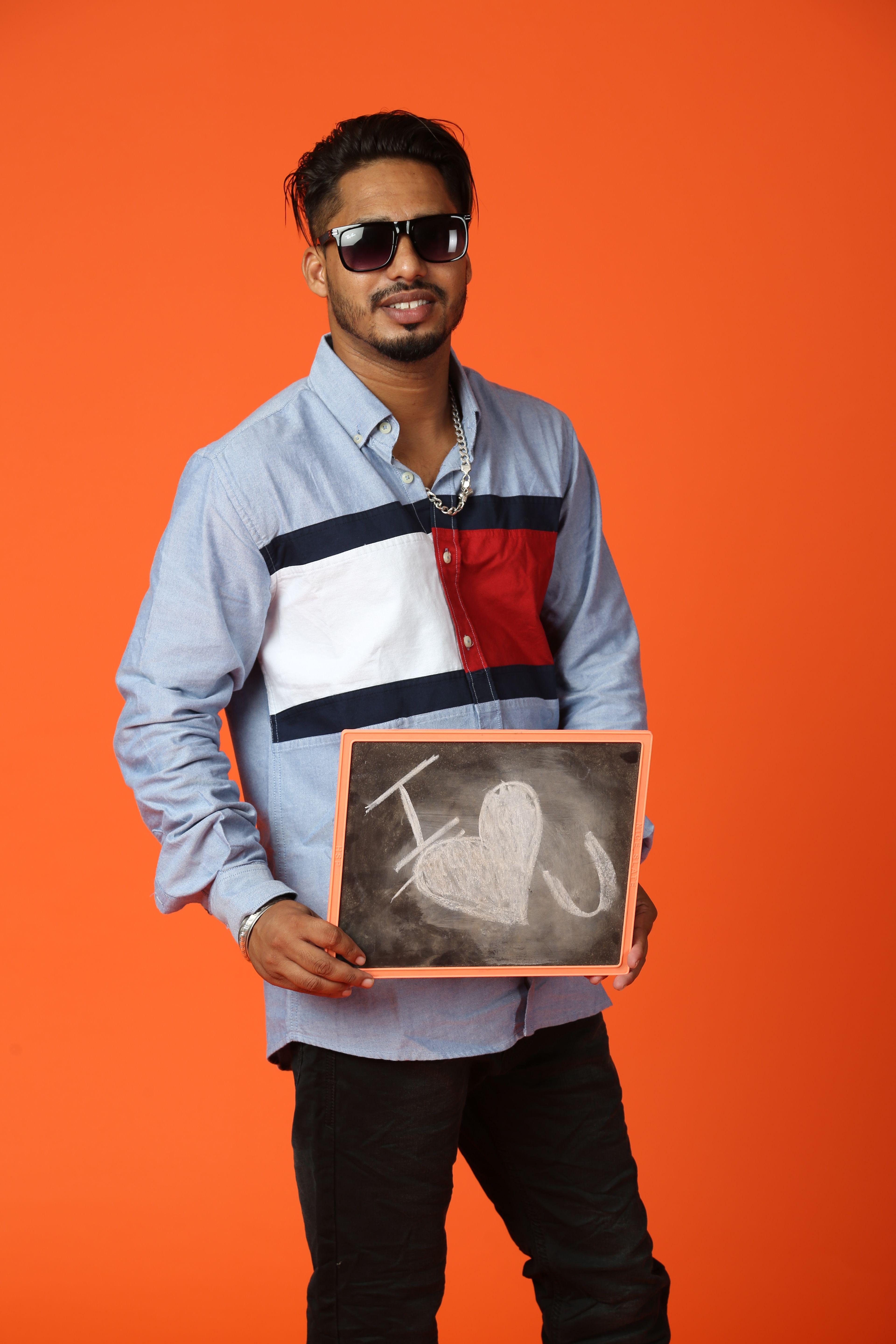 Man holding chalkboard with 'I Love You' heart drawing on orange background, depicting love message.