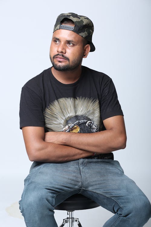 A Bearded Man in Black Shirt Sitting on the Stool with His Arms Crossed