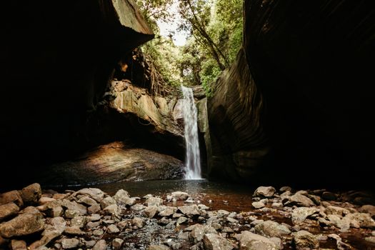 A beautiful waterfall cascading in a rocky cavern surrounded by lush greenery.