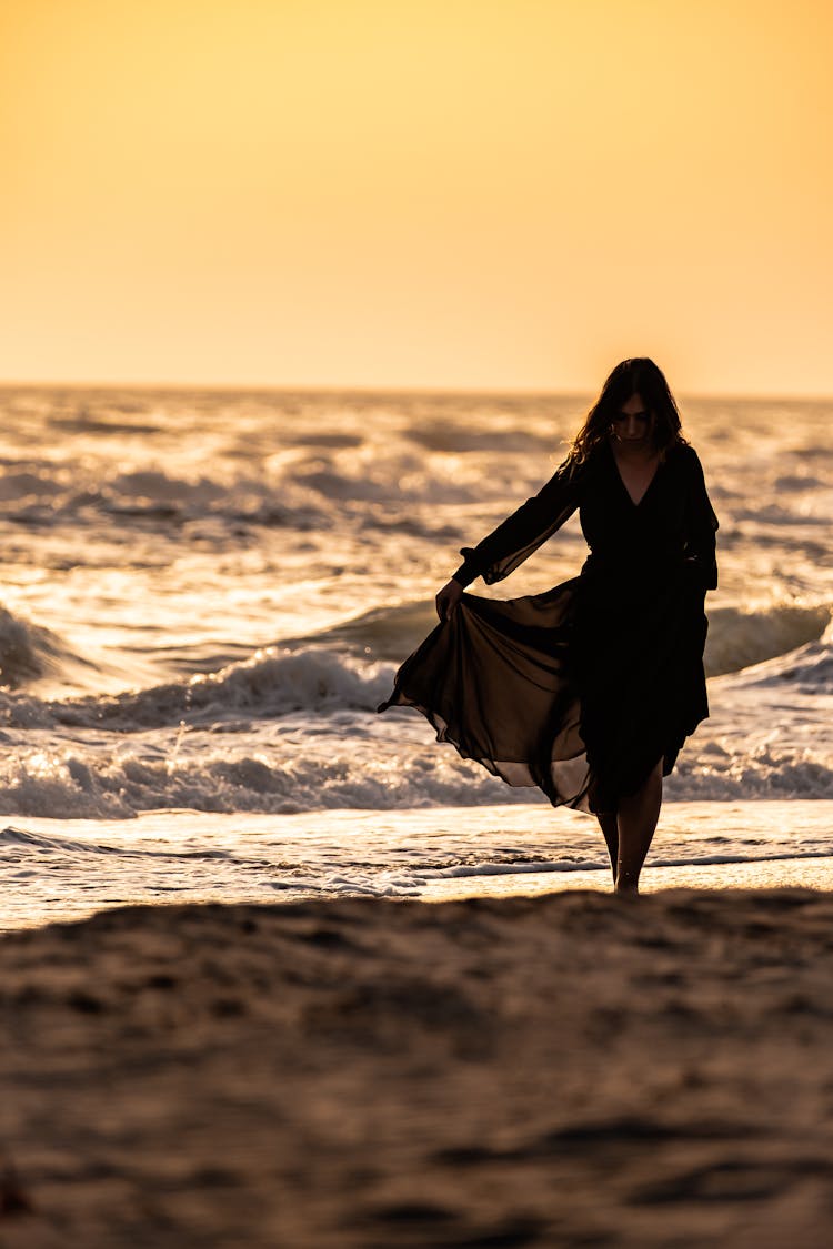 Woman Walking On The Beach At Sunset 