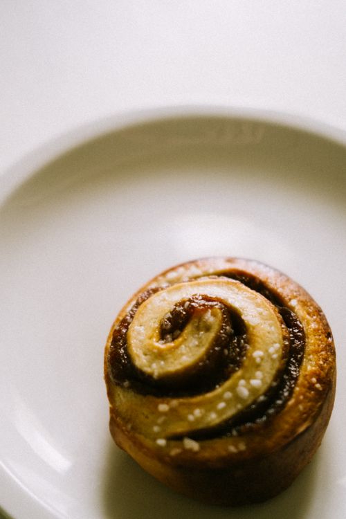 Free A close-up of a freshly baked cinnamon roll on a white plate, perfect for dessert lovers. Stock Photo