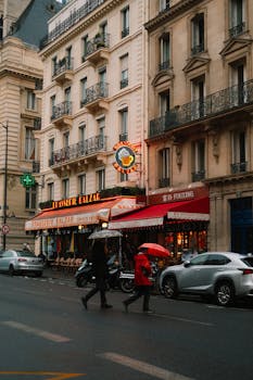 A rainy day in Paris with people crossing the street under umbrellas.