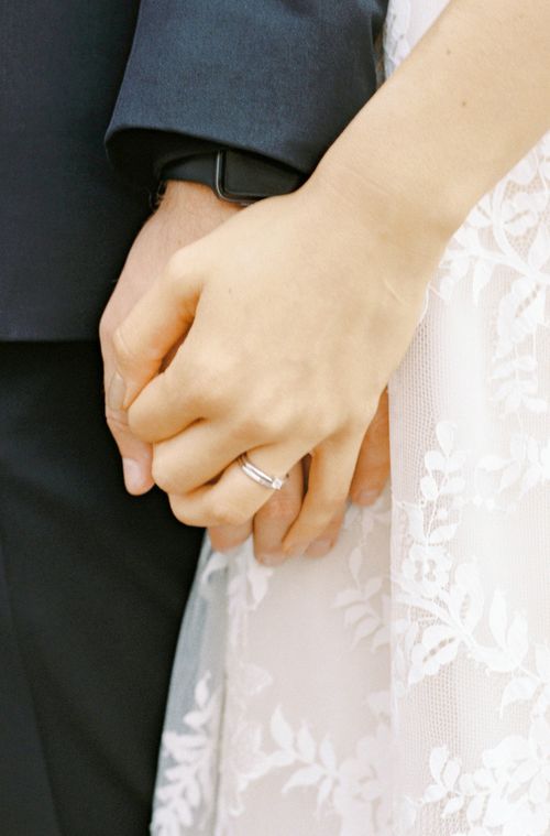 Free Intimate close-up of a bride and groom holding hands on their wedding day, emphasizing romance and unity. Stock Photo