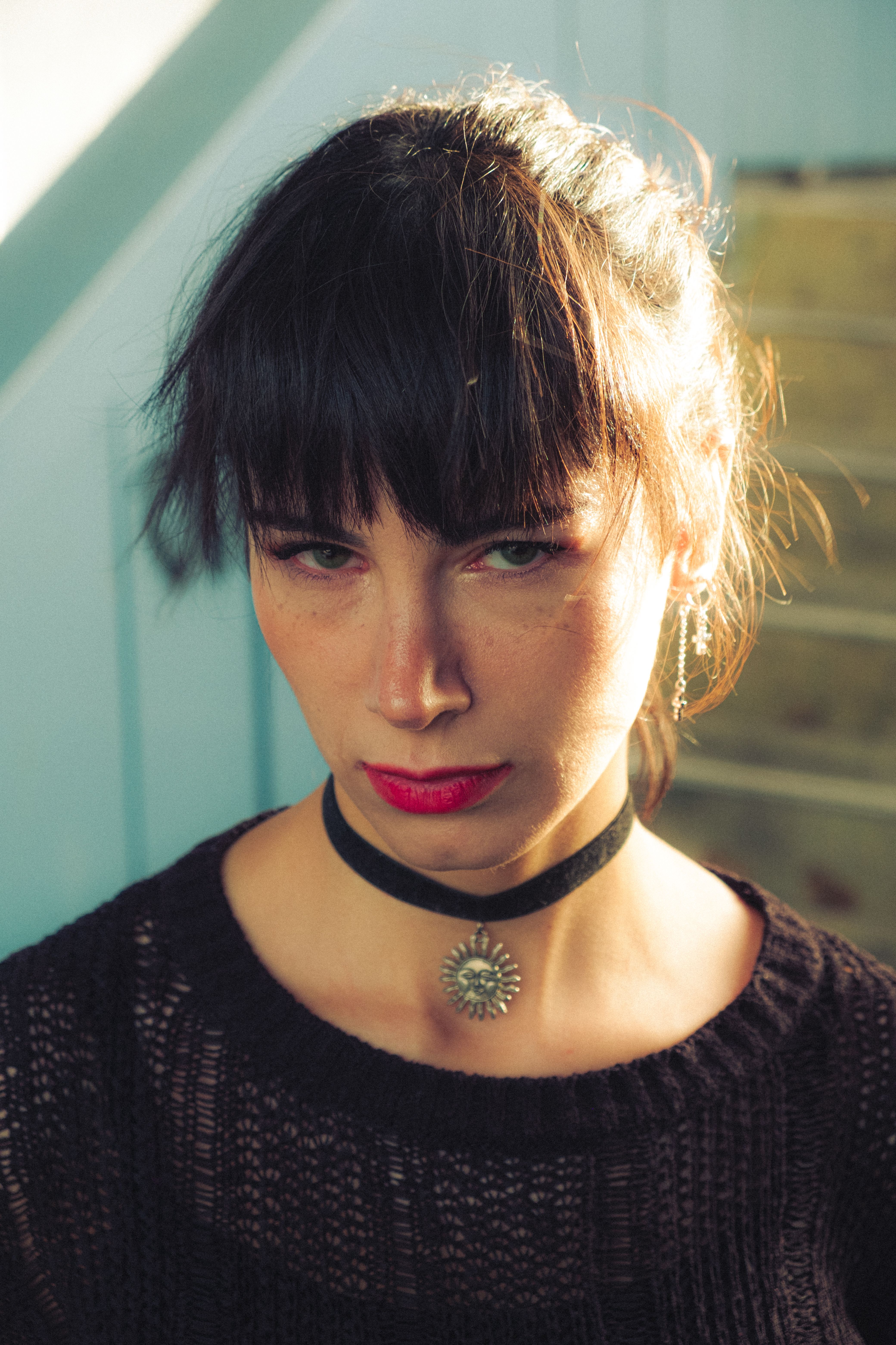 A striking portrait showcasing a woman with a black choker and bangs, captured in soft light.