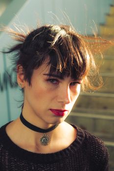 Close-up portrait of a woman with bangs and choker in natural sunlight.