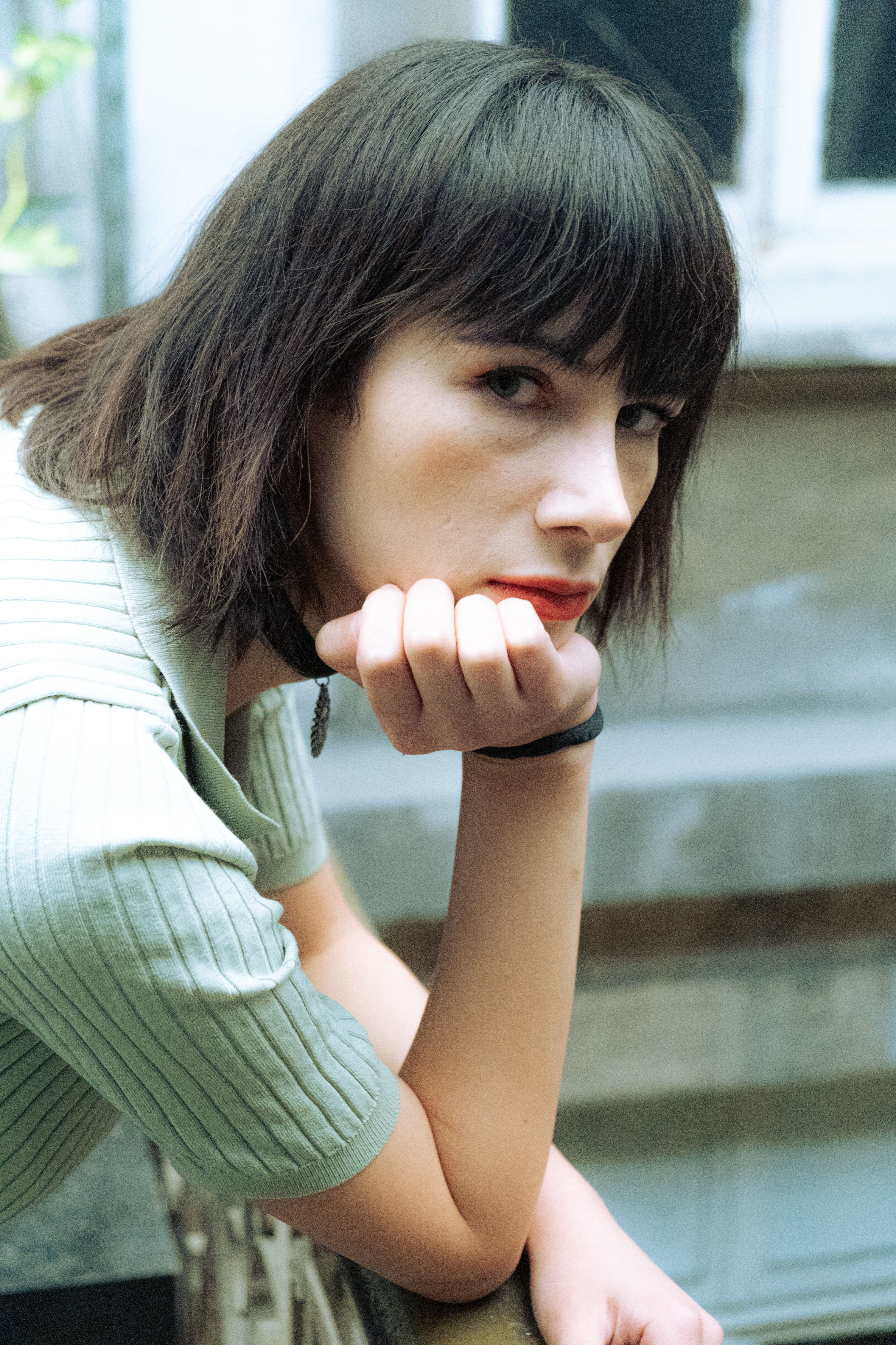 Close-up of a woman with short hair resting her chin on her hand, displaying a thoughtful expression.