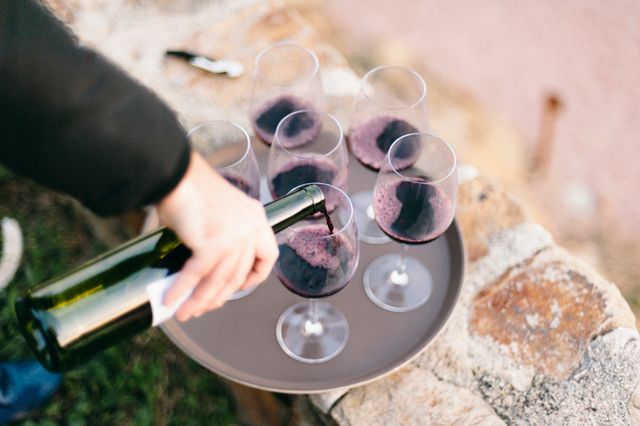 Red wine being poured into glasses on a tray outdoors. Photo by Alina Skazka on Pexels