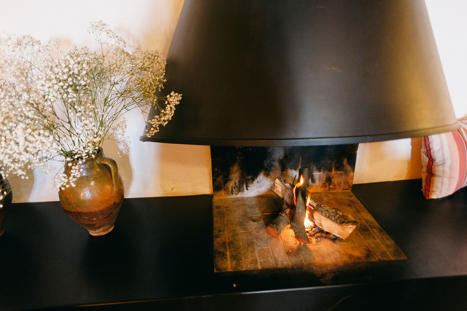 Warm indoor setting featuring a cozy fireplace and babys breath flowers in a rustic vase.