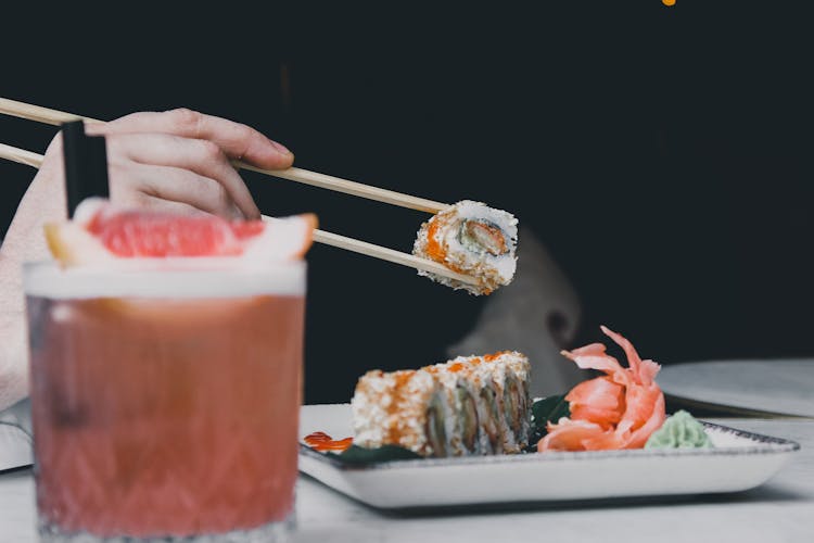 Close-up Of Person Eating Sushi With Chopsticks