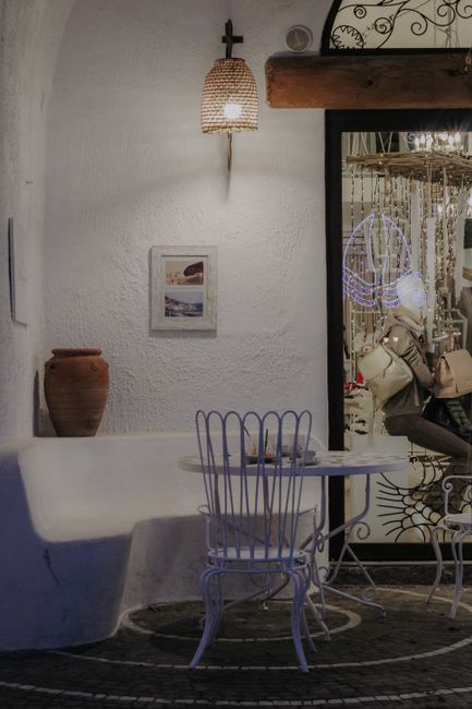A cozy café corner featuring an empty table and chair with warm lighting.