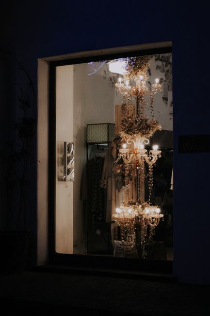 Elegant store window showcasing a beautifully illuminated chandelier inside.