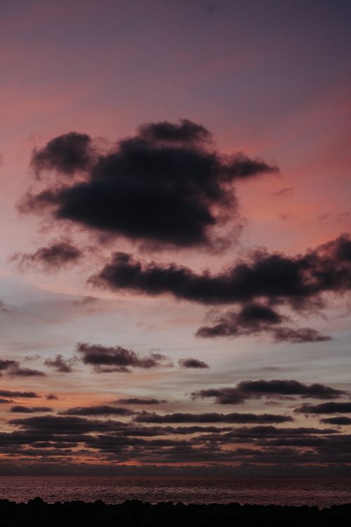 Free A captivating view of a dramatic sunset sky with striking silhouetted clouds over the horizon. Stock Photo