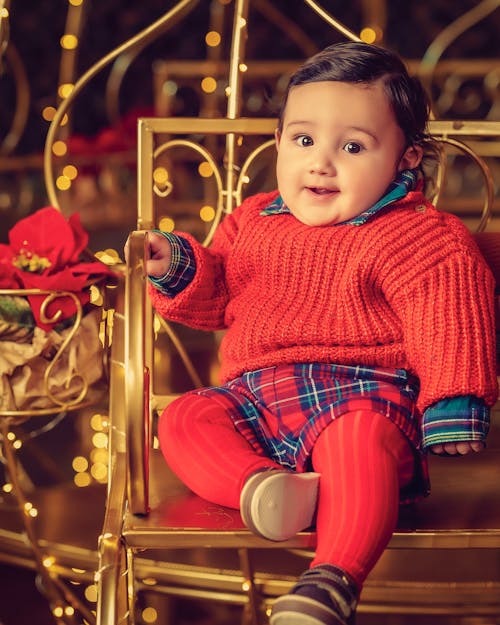 Free Baby in Red Sweater Sitting on Golden Chair Stock Photo