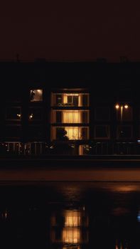 Building facade with warm light reflections on wet street in Moscow, Russia at night.