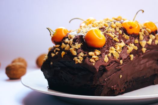 Delicious homemade chocolate cake topped with vibrant berries and chopped walnuts, perfect for dessert lovers.