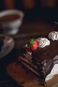Close-up of a chocolate cake roll topped with strawberries and cream swirls.