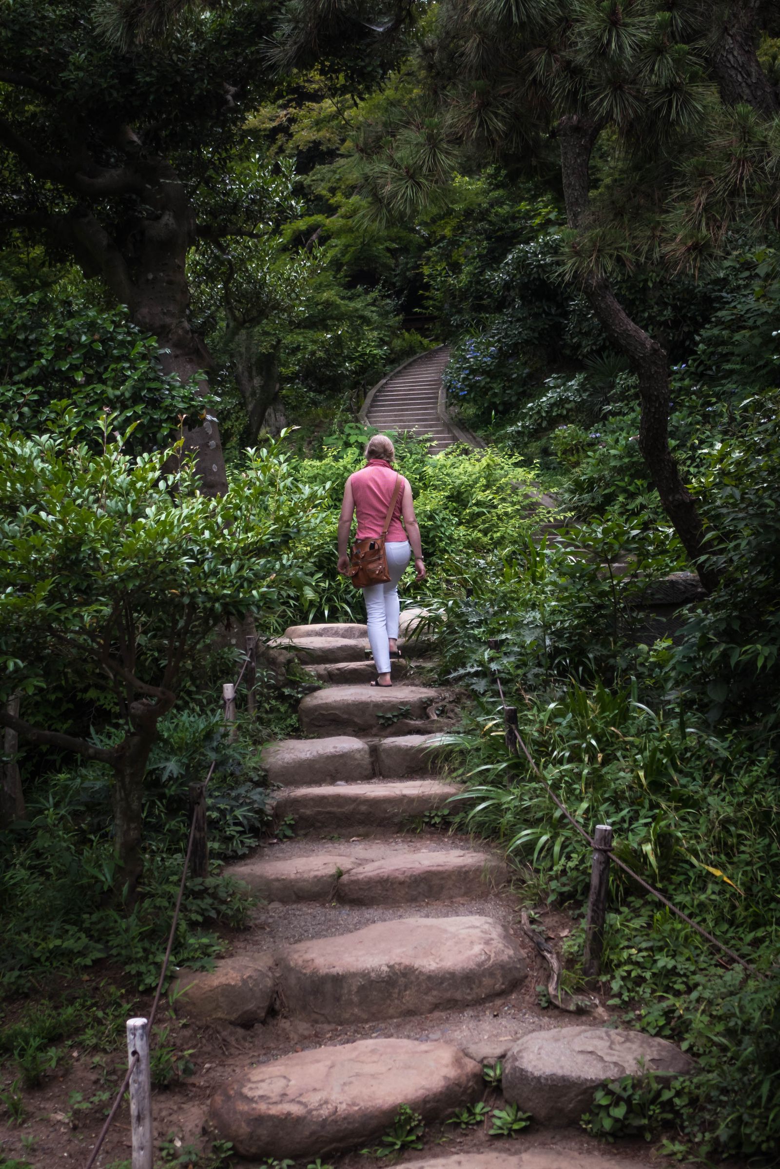 Woman walking up stone steps on a leafy garden path