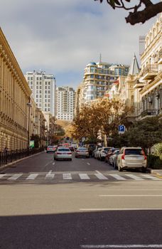 City street scene with cars, buildings, and crosswalk under a bright sky.