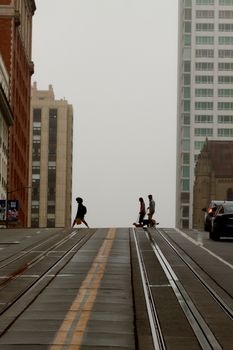 A foggy urban street with pedestrians crossing and iconic architecture in the background.