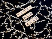 Scrabble tiles spell out 'Happy New Year' with festive decorations in Paris, France.